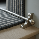 Brushed nickel stair rods fitted on charcoal striped runner — minimalist British interior
