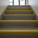 Yellow DDA-compliant anti-slip tape on public building stair nosings for accessibility compliance