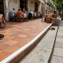 Flexible PVC tile trim creating seamless edge between terracotta tiles and concrete sidewalk at outdoor restaurant