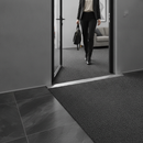 49mm wide aluminium door threshold strip in Inox — installed between floors at UK home doorway with person using it