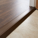 Champagne anodised aluminium ramp threshold fitted in a hallway between dark walnut LVT and lower cream travertine-effect tile