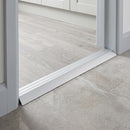 Silver aluminium ramp threshold fitted in a kitchen doorway between grey wood-effect LVT and lower concrete-effect porcelain tile
