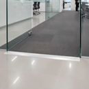 Wide aluminium floor transition bar installed at commercial UK office doorway between tiles and carpet tiles