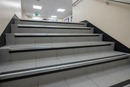 Anti-slip ramp profile stair nosing on commercial UK school staircase - black PVC insert providing step edge safety