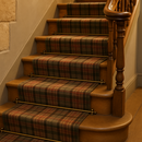 Antique brass stair rods on traditional British country house staircase with tartan runner carpet
