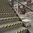 Black and yellow hazard stair treads on industrial steps in UK warehouse