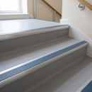 Aluminium bullnose stair nosing with a cobalt blue anti-slip insert fitted to light grey vinyl steps in a school stairwell
