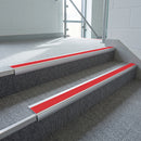 Aluminium bullnose stair nosing with a red anti-slip insert fitted to grey carpet steps in a leisure centre stair