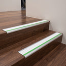 Aluminium bullnose stair nosing with a white anti-slip insert and green photoluminescent strip fitted to dark timber stairs