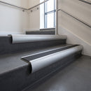 Aluminium bullnose stair nosing with Black Smooth Textured PVC infill, fitted to concrete steps in a commercial stairwell