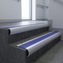 Aluminium bullnose stair nosing with Mid Blue Castellated PVC infill, fitted to concrete steps in a commercial stairwell
