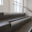 Mill Aluminium bullnose stair nosing with Black Anodised Aluminium infill, fitted to concrete steps in a commercial stairwell