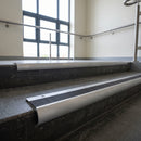 Mill Aluminium bullnose stair nosing with Black Castellated PVC infill, fitted to concrete steps in a commercial stairwell