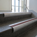 Mill Aluminium bullnose stair nosing with Claret Castellated PVC infill, fitted to concrete steps in a commercial stairwell