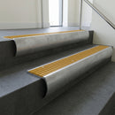 Mill Aluminium bullnose stair nosing with Gold Castellated PVC infill, fitted to concrete steps in a commercial stairwell