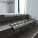 Mill Aluminium bullnose stair nosing with Peat Castellated PVC infill, fitted to concrete steps in a commercial stairwell