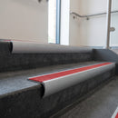 Mill Aluminium bullnose stair nosing with Poppy Castellated PVC infill, fitted to concrete steps in a commercial stairwell