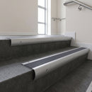 Mill Aluminium bullnose stair nosing with Regency Castellated PVC infill, fitted to concrete steps in a commercial stairwell
