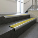 Mill Aluminium bullnose stair nosing with Yellow Castellated PVC infill, fitted to concrete steps in a commercial stairwell