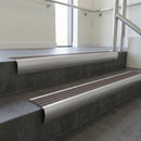 Aluminium bullnose stair nosing with Peat Castellated PVC infill, fitted to concrete steps in a commercial stairwell