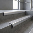 Aluminium bullnose stair nosing with Polar Grey Castellated PVC infill, fitted to concrete steps in a commercial stairwell