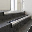 Polished Aluminium bullnose stair nosing with Black Anodised Aluminium infill, fitted to concrete steps in a commercial stairwell
