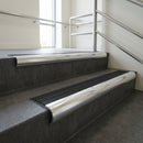 Polished Aluminium bullnose stair nosing with Black Castellated PVC infill, fitted to concrete steps in a commercial stairwell