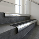Polished Aluminium bullnose stair nosing with Black Olympic Grip infill, fitted to concrete steps in a commercial stairwell