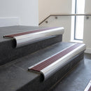 Polished Aluminium bullnose stair nosing with Claret Castellated PVC infill, fitted to concrete steps in a commercial stairwell