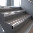 Polished Aluminium bullnose stair nosing with Fawn Castellated PVC infill, fitted to concrete steps in a commercial stairwell