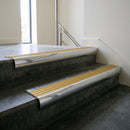 Polished Aluminium bullnose stair nosing with Gold Castellated PVC infill, fitted to concrete steps in a commercial stairwell