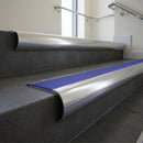Polished Aluminium bullnose stair nosing with Mid Blue Castellated PVC infill, fitted to concrete steps in a commercial stairwell