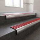 Polished Aluminium bullnose stair nosing with Poppy Castellated PVC infill, fitted to concrete steps in a commercial stairwell