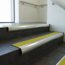 Polished Aluminium bullnose stair nosing with Yellow Castellated PVC infill, fitted to concrete steps in a commercial stairwell