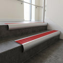 Aluminium bullnose stair nosing with Poppy Castellated PVC infill, fitted to concrete steps in a commercial stairwell