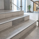 Matt silver aluminium bullnose tile-in stair nosing fitted to porcelain-tiled steps in a commercial building