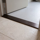 Bronze 38mm aluminium cover strip screw fixed across a doorway between limestone tile and grey vinyl