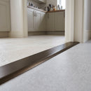 38mm aluminium cover strip in Bronze fitted in a kitchen doorway between pale limestone tile and grey vinyl