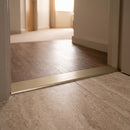38mm aluminium cover strip in Light Bronze fitted in a hotel corridor doorway between walnut LVT and travertine tile