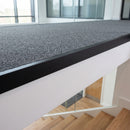 Matt black aluminium landing strip fitted along the edge of a carpeted landing above a staircase
