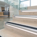 Black insert aluminium LED stair nosing on pale limestone office steps with lit riser diffuser