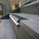 End profile close-up of aluminium LED stair nosing showing grit anti-slip insert and lit frosted diffuser