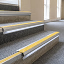 Yellow insert aluminium LED stair nosing on grey carpeted leisure centre steps with lit riser strip