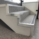 Mill aluminium pre-formed stair side angles finishing the open-string edge of carpeted steps in an office stairwell