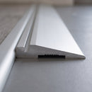 Close-up of aluminium ramp trim cut end behind a stair nosing sloping down to grey vinyl