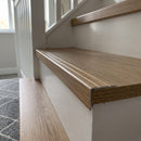 Oak effect aluminium stair nosing 25mm x 10mm fitted over the front edge of a laminate stair tread above a white painted riser