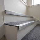 Silver anodised aluminium 35x35mm ribbed stair nosing fitted to grey carpeted steps in an office stairwell