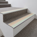 Beige insert aluminium stair nosing fitted to carpet tile treads in an apartment block communal staircase