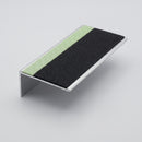 Aluminium stair nosing 57x32mm shown alone on a studio background, green photoluminescent strip along the leading edge and black PVC anti-slip insert behind it