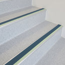 Cobalt blue insert aluminium stair nosing fitted to pale speckled vinyl treads in a leisure centre staircase